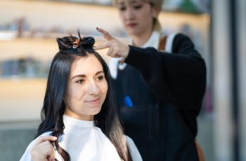 Caucasian women with Hair stylish while do hair cut and wearing surgical face mask while styling hair for client. Professional occupation, beauty and fashion service new normal